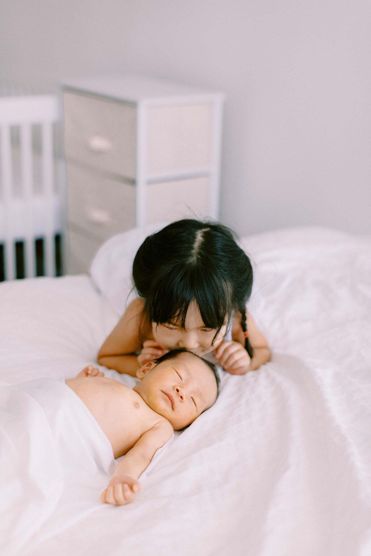toddler kissing her baby brother's head