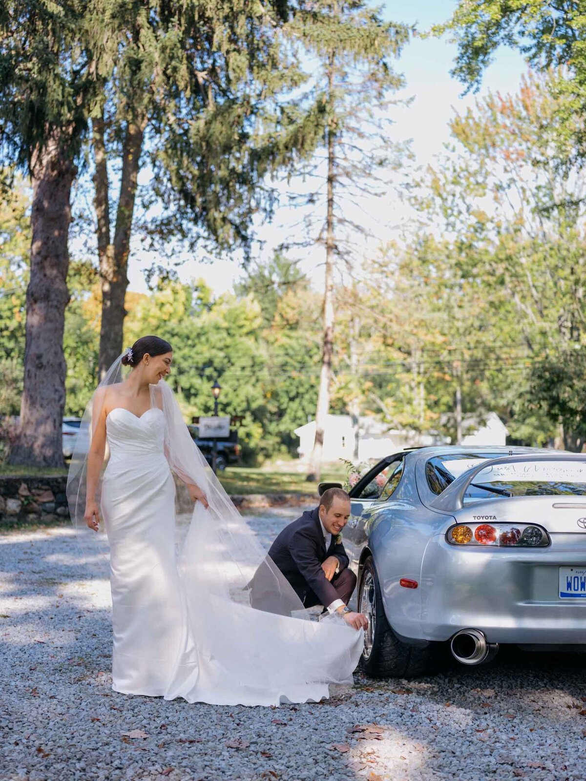 Bride and groom beside their favorite sports car on their wedding day.
