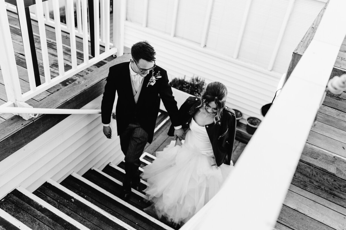 Black and white photo of Bride and Groom walking up staircase of church