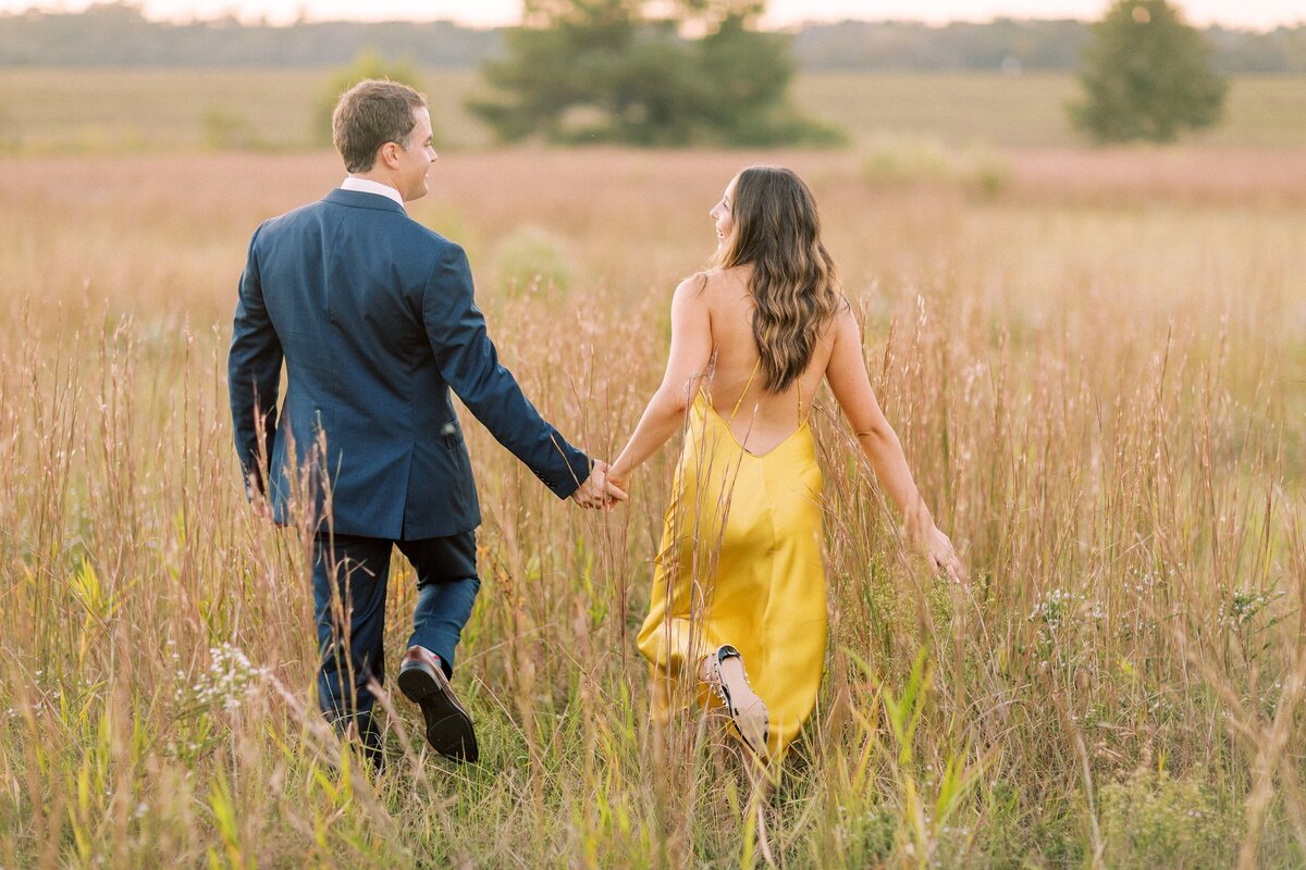 couple walks through a grassy field