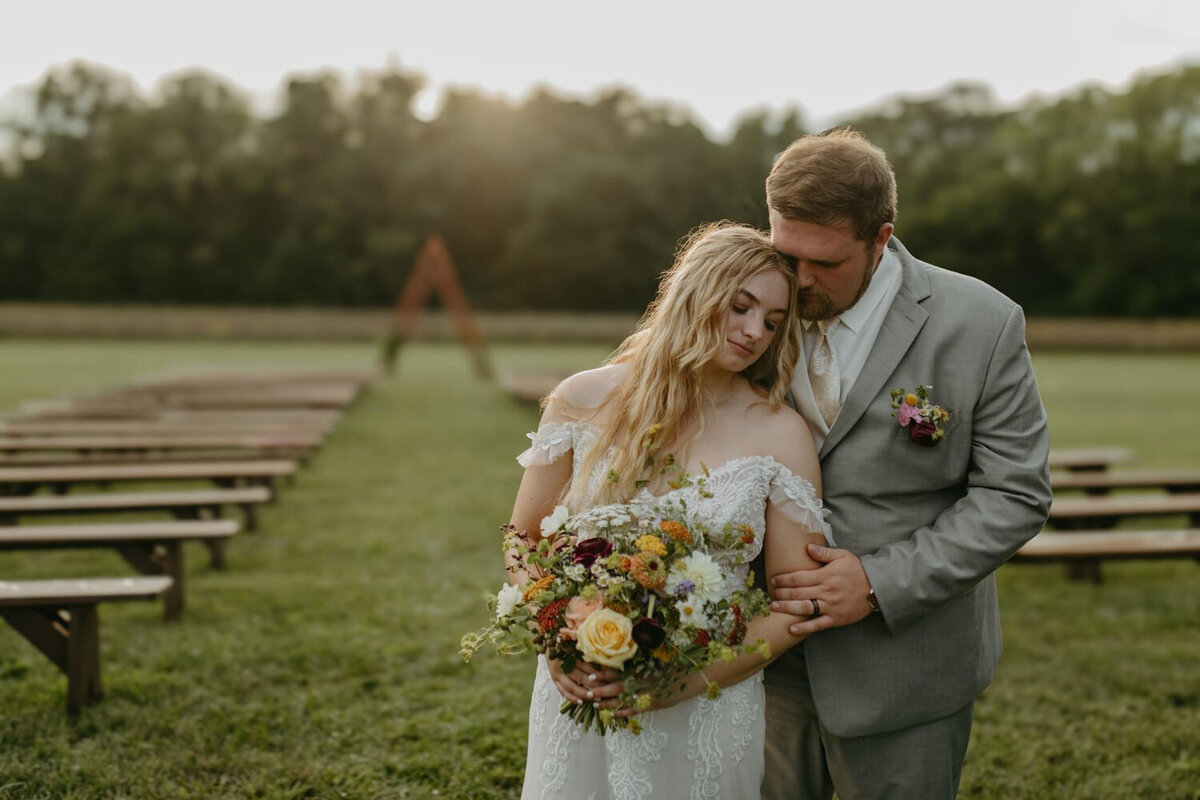 Bride and groom embracing in an outdoor ceremony setting.