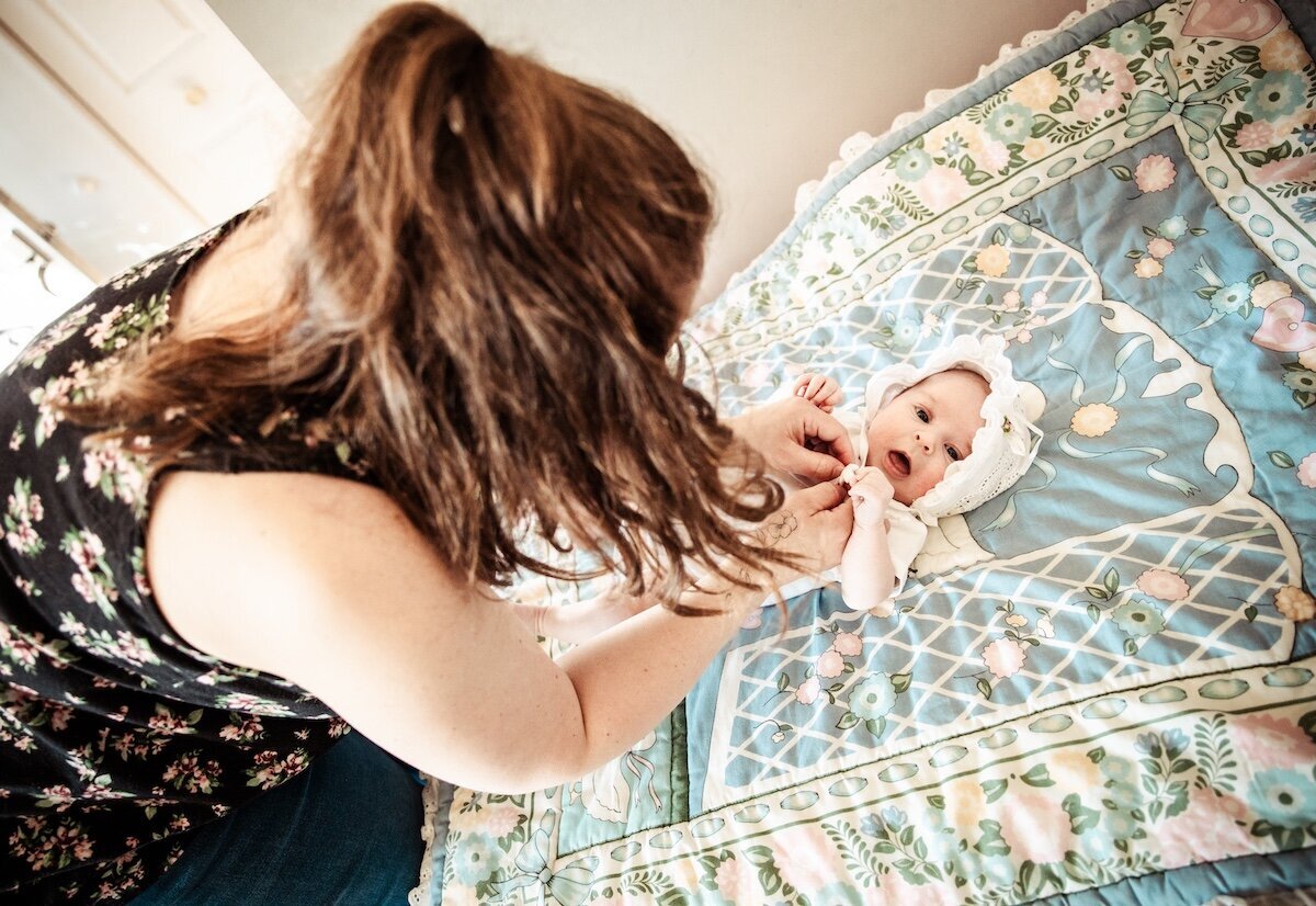 a mom dressing her newborn baby girl