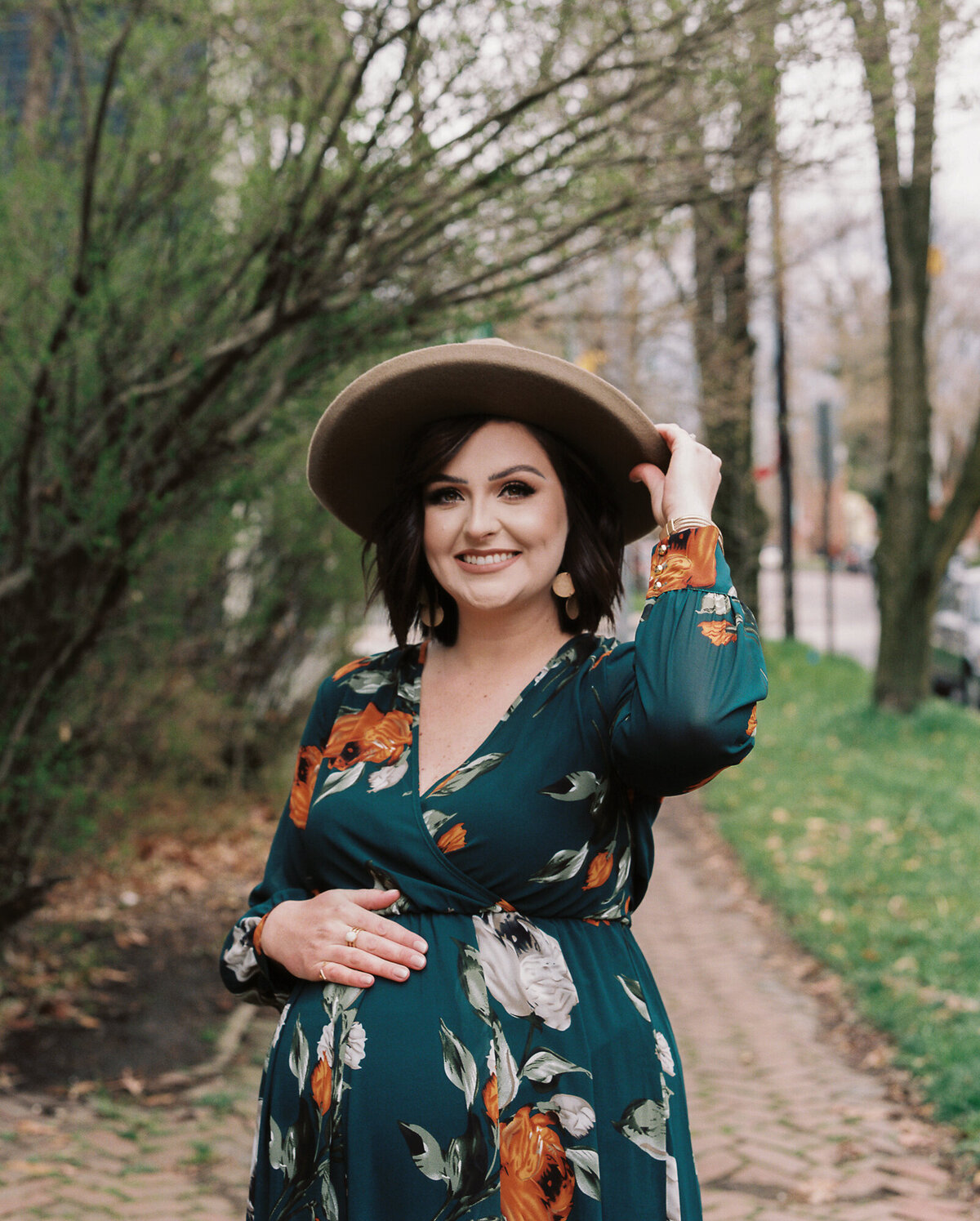 Glowing mother poses with her favorite hat during her maternity session