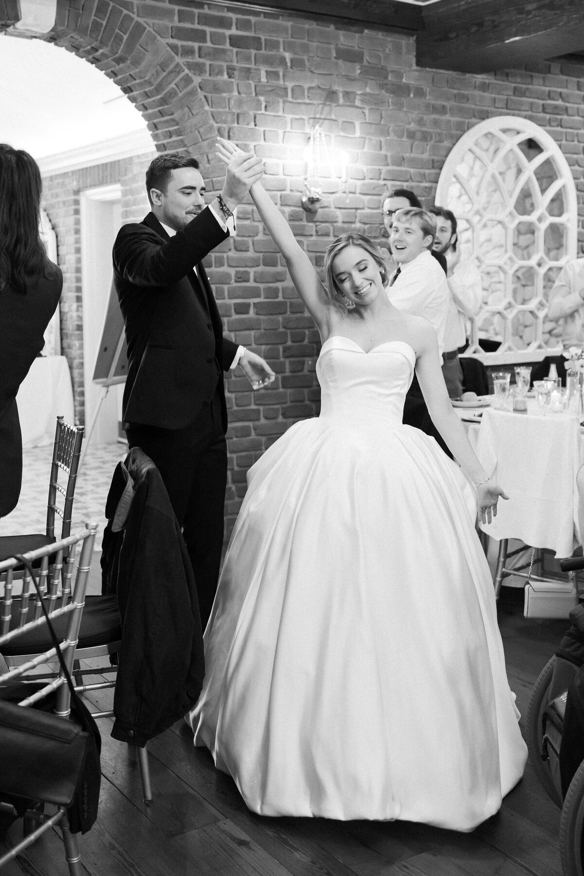 Wedding at the Estate at River Run in Maidens, VA | Wedding Photographer in Richmond | black and white image of bride and groom entering their Estate at River Run Tuscan Ballroom wedding reception with guests clapping in the background