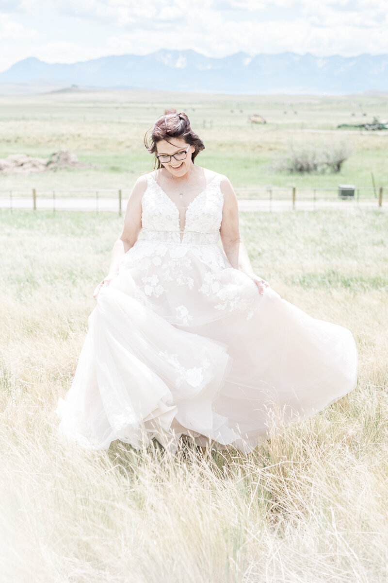 Bride spinning in front of the rocky mountains in her wedding dress in a light and bright photography style in Bozeman, MT