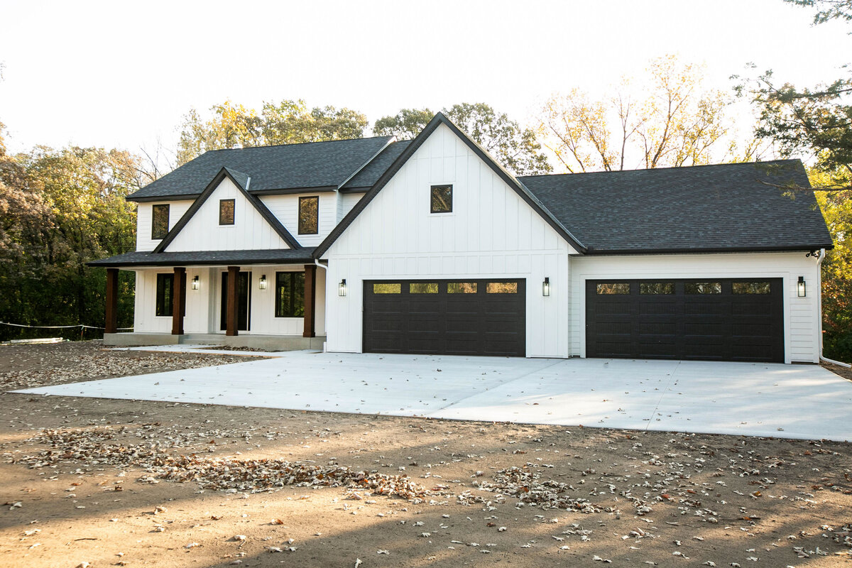 Exterior view of custom home in Big Lake Township, Minnesota with farmhouse details, cream siding, wood pillars and front porch built by Cornerstone Custom Builds