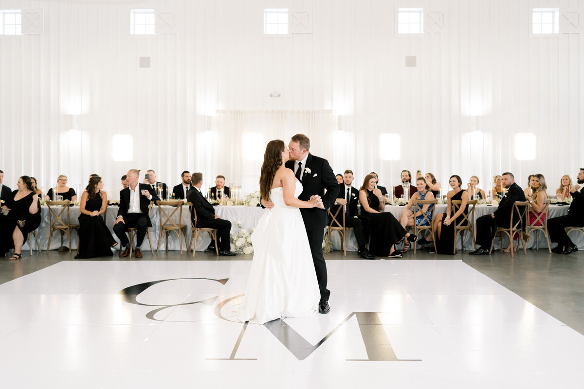 Bride and groom's first dance on white dance floor with black monogram