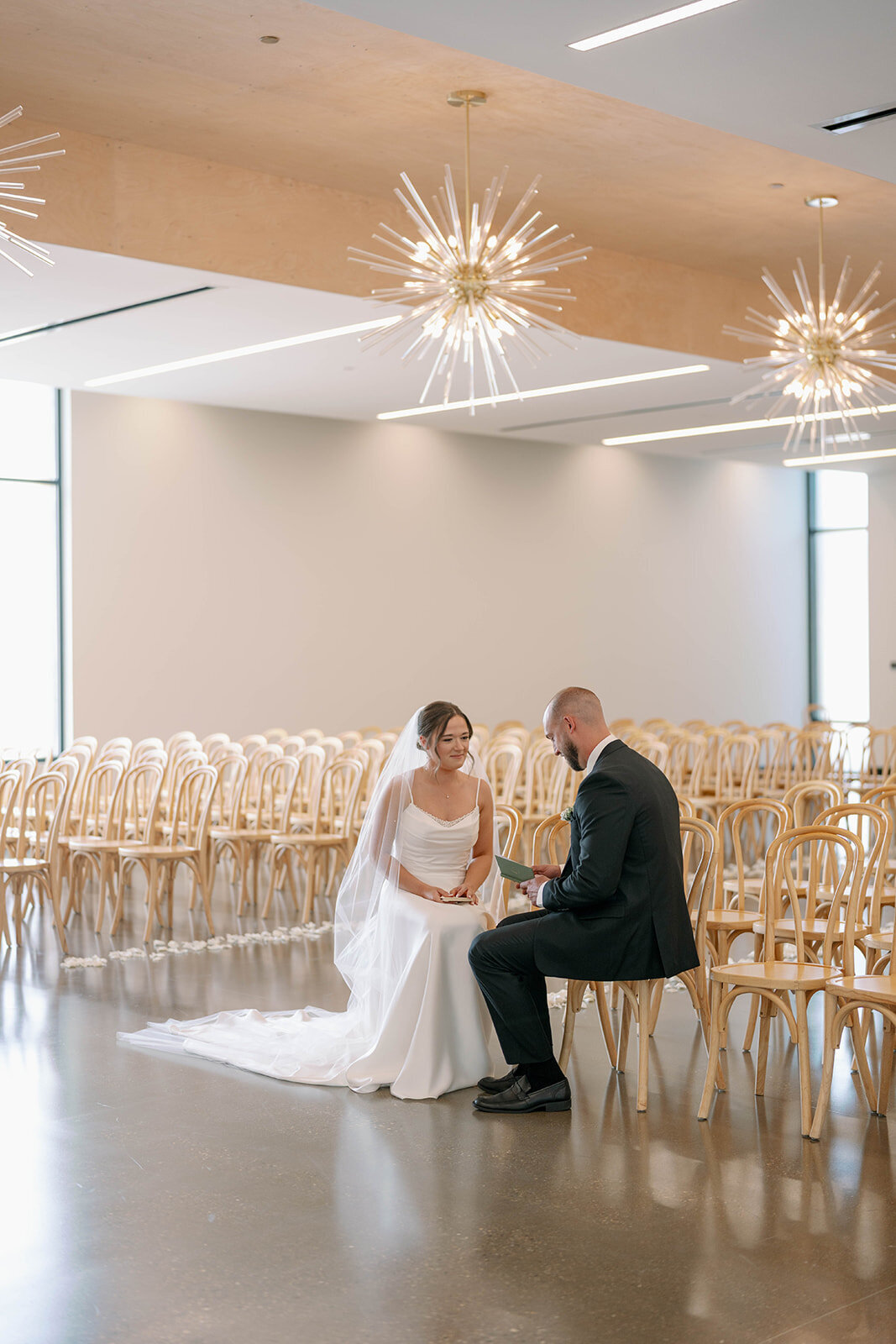 Bride and groom sitting together in the empty ceremony room at Leona Road sharing private vows before their wedding in Grand Rapids MI.