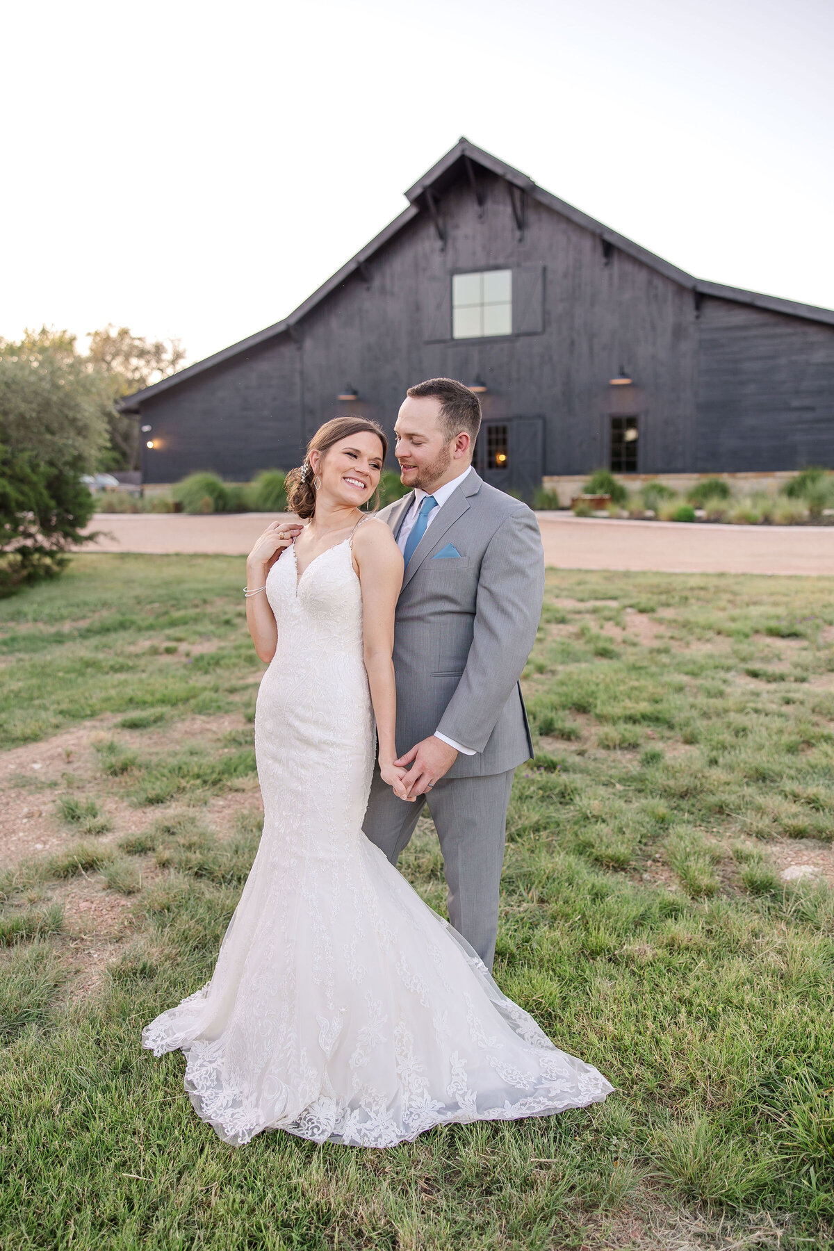 bride leans into groom in field at sunset at Austin area wedding venue