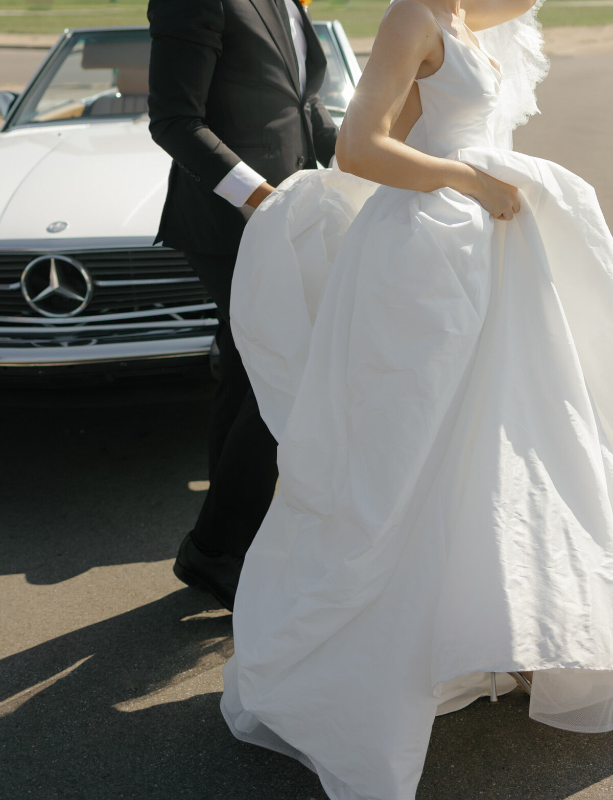 candid wedding photo of groom helping bride with her dress in Detroit, Michigan