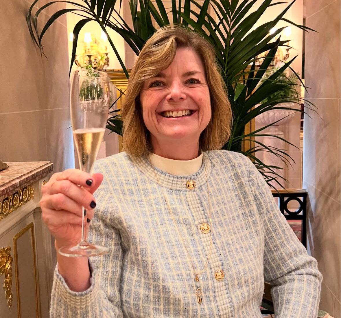 Photo of Kelly with a drink in a glass by a plant