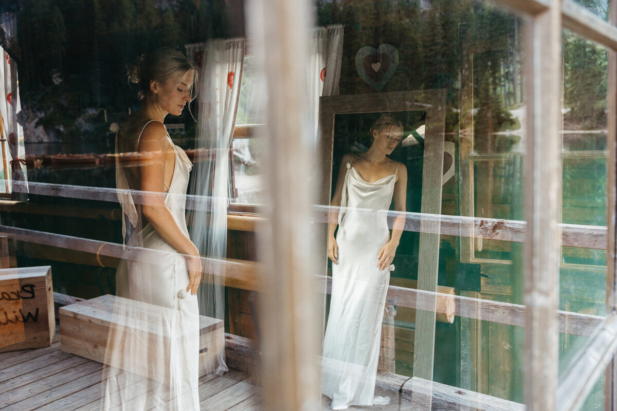 Bride standing in window light at Lago di Braies boathouse