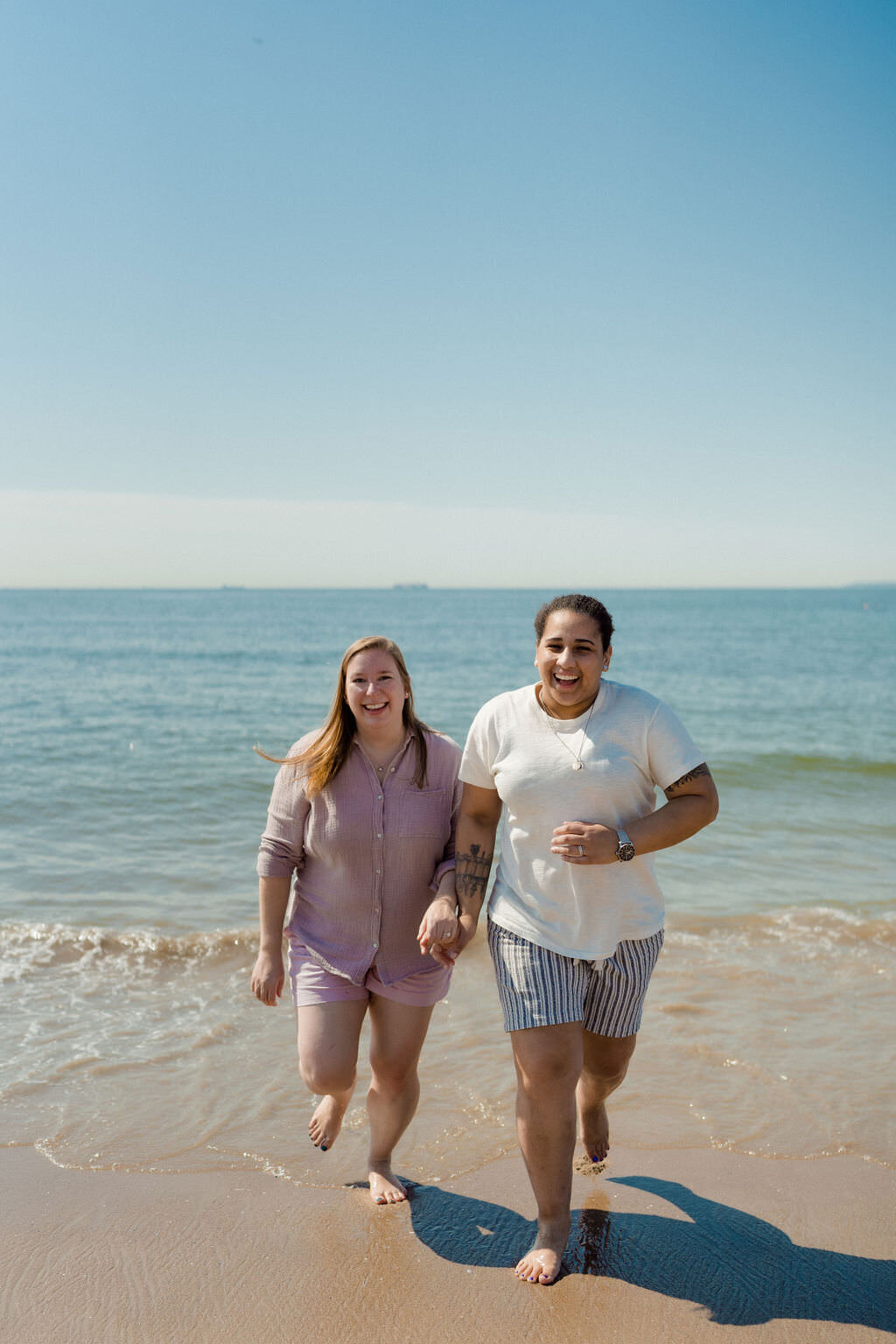 couple holding hands and smiling as they walk out of the water