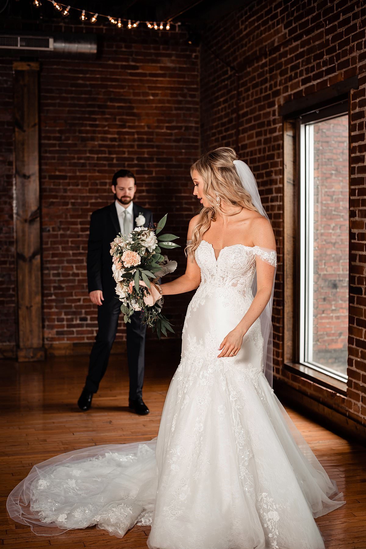 Bride showing off her gorgeous lace wedding dress to her husband during their first look