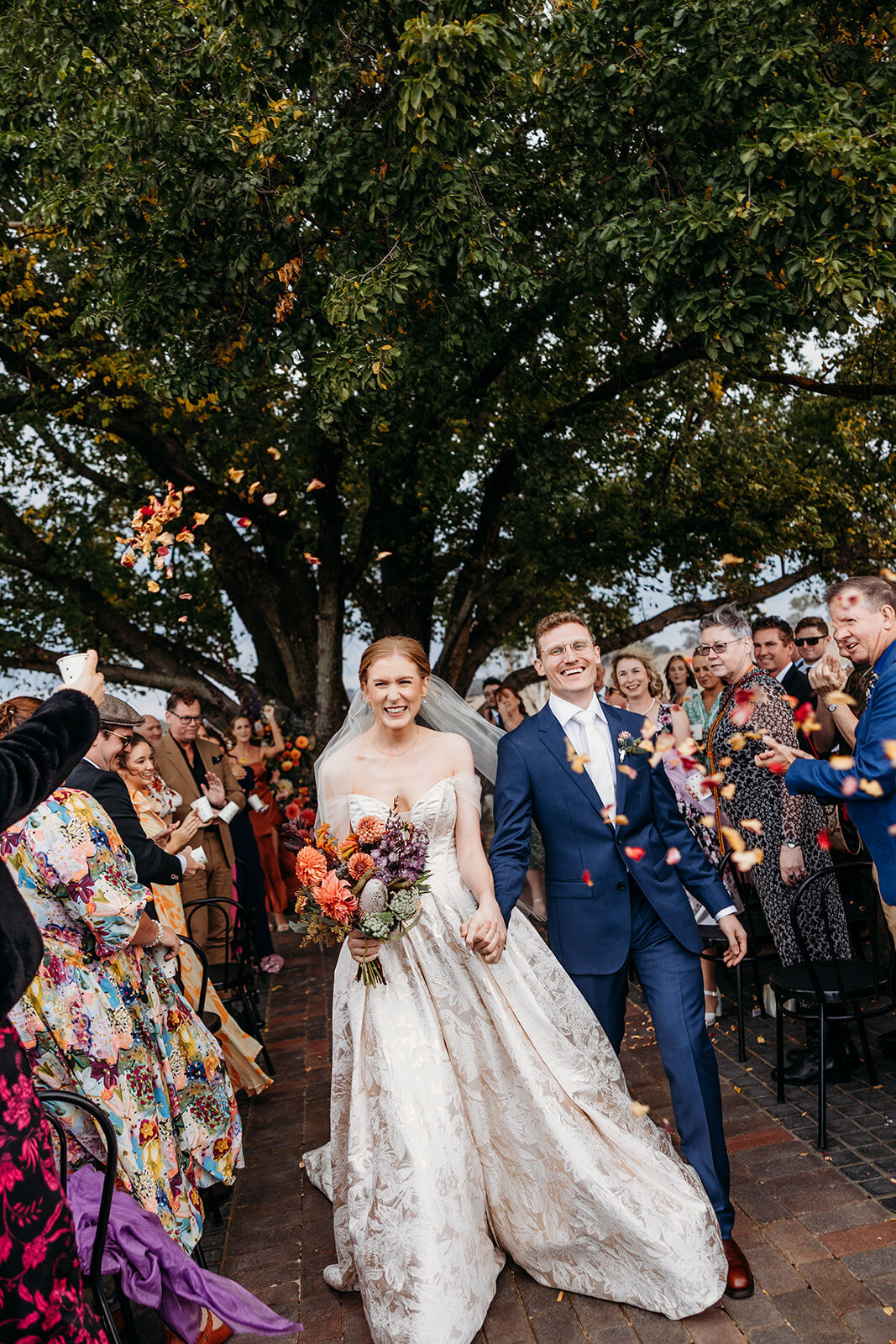 Bride and groom smiling during their confetti exit after wedding ceremony at Petrichor Farm