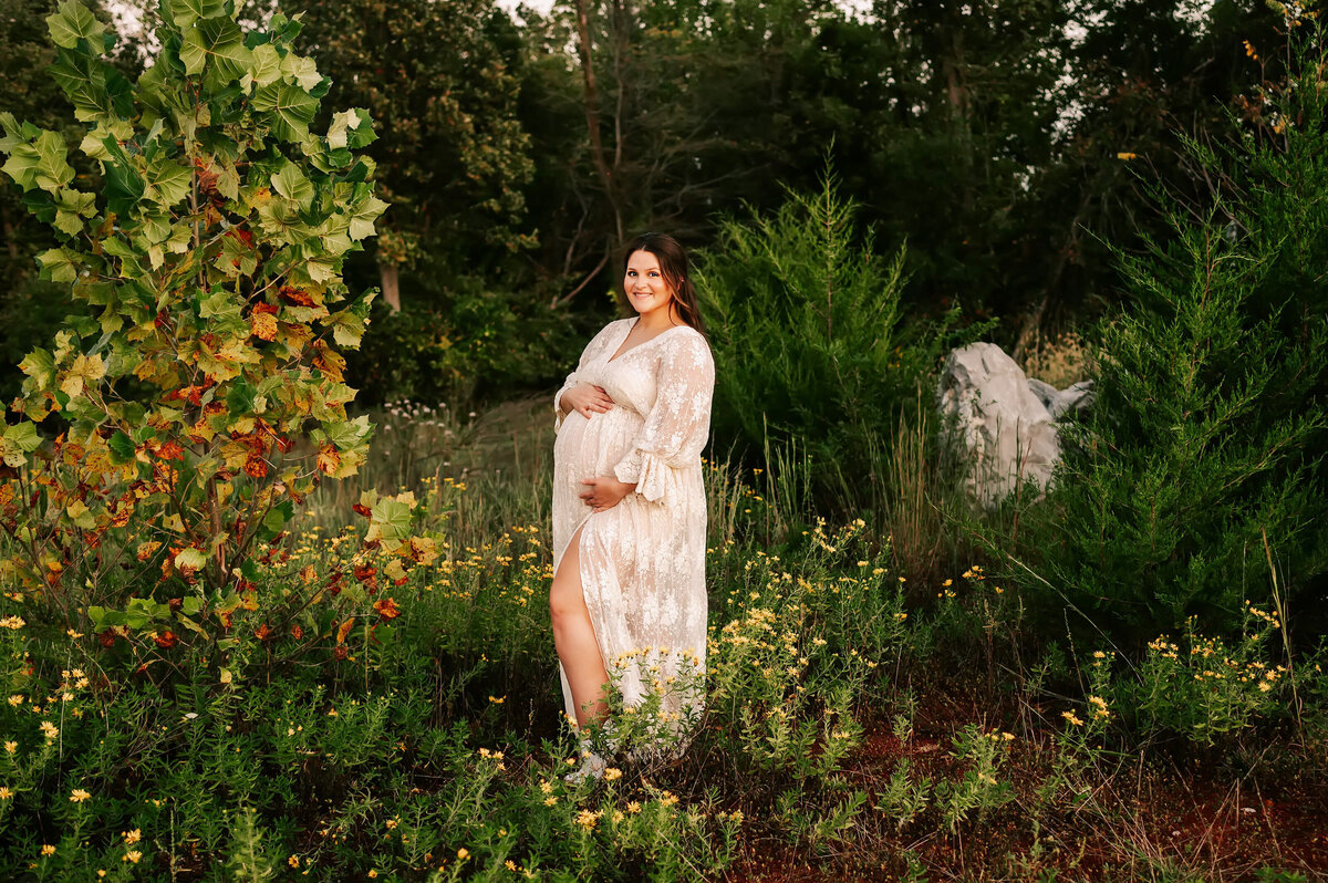 maternity photo of pregnant mom smiling in lace dress dress in a field in Branson MO