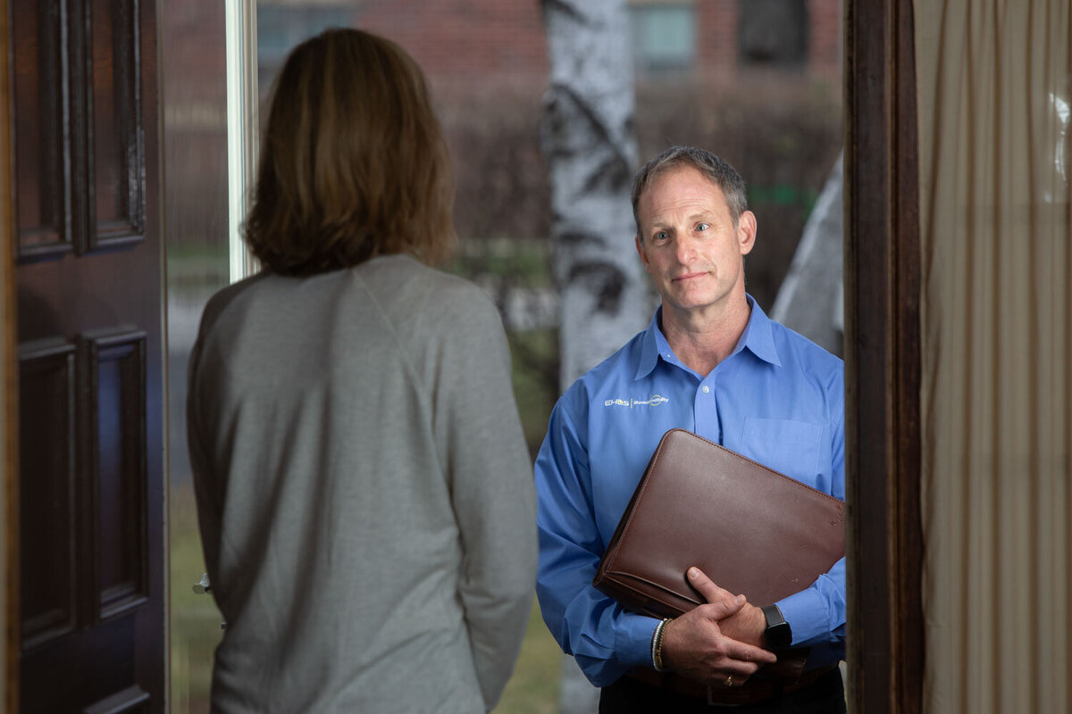 A man in a blue shirt is holding a briefcase and talking to a woman