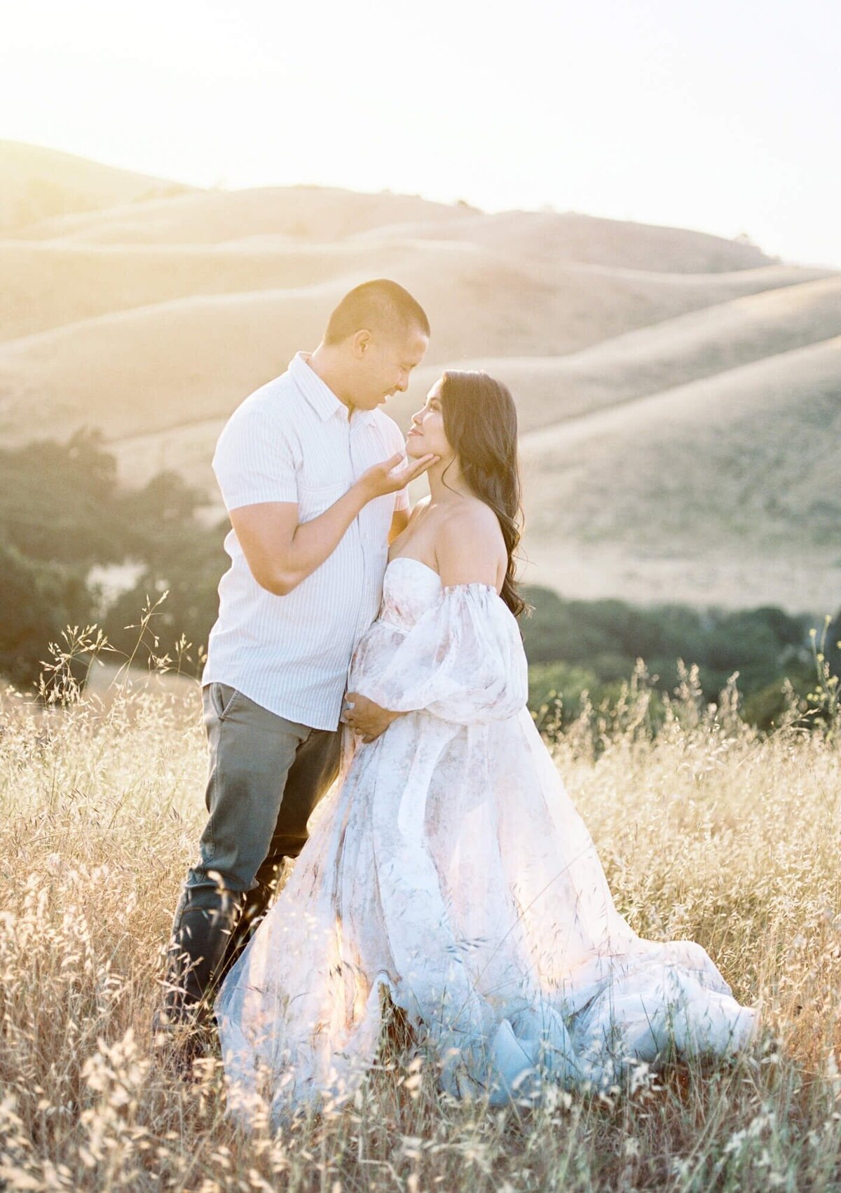 Pregnant woman and her husband framing her belly in a tulle dress taken by one of the top San Francisco Maternity Photographers Laurel Smith.