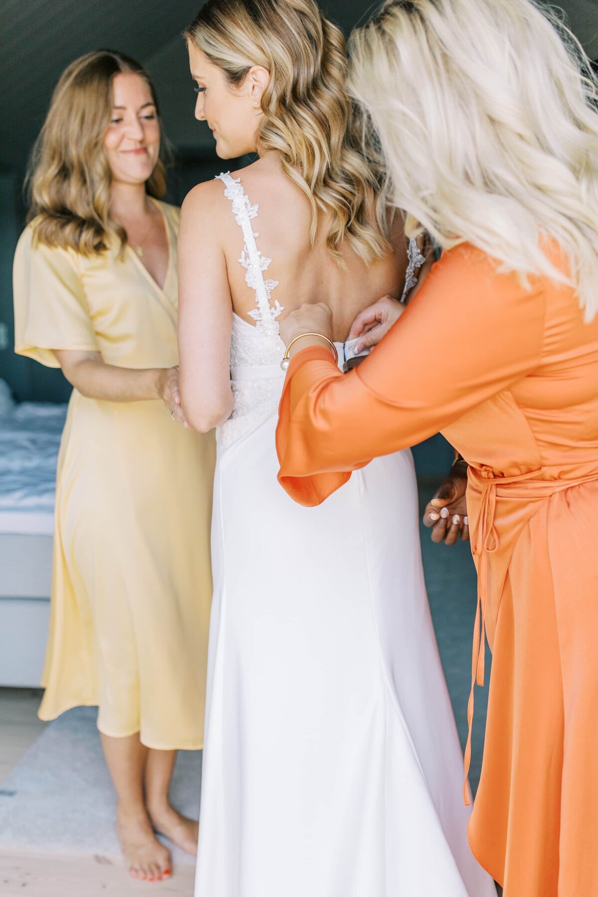 Brudtärnor hjälper en brud med bröllopsklänningen
