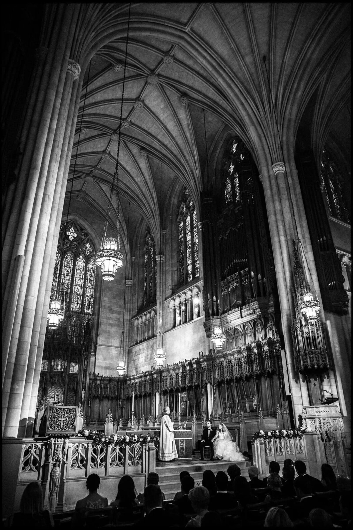 Wide shot of a wedding ceremony in the grand interior of Duke Chapel, with a couple at the altar and guests seated
