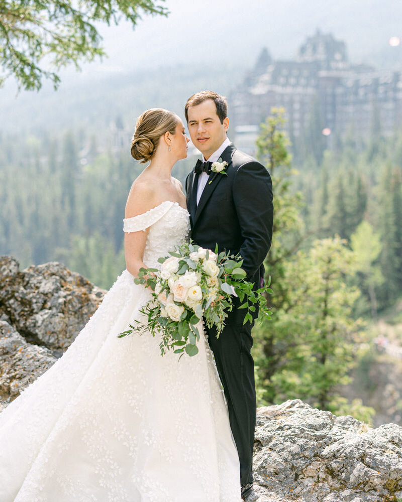 This elegant photograph captures the bride and groom holding each other in Banff National Park, with the iconic Banff Springs Hotel as the backdrop. The luxurious setting of their high-end wedding adds sophistication and grandeur to the intimate moment.