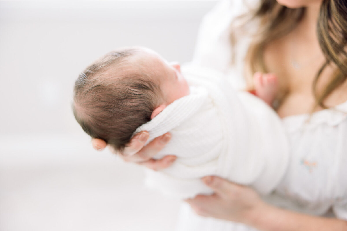 swaddled baby in mom's hands Tampa newborn photographer Tina Marie Studio.
