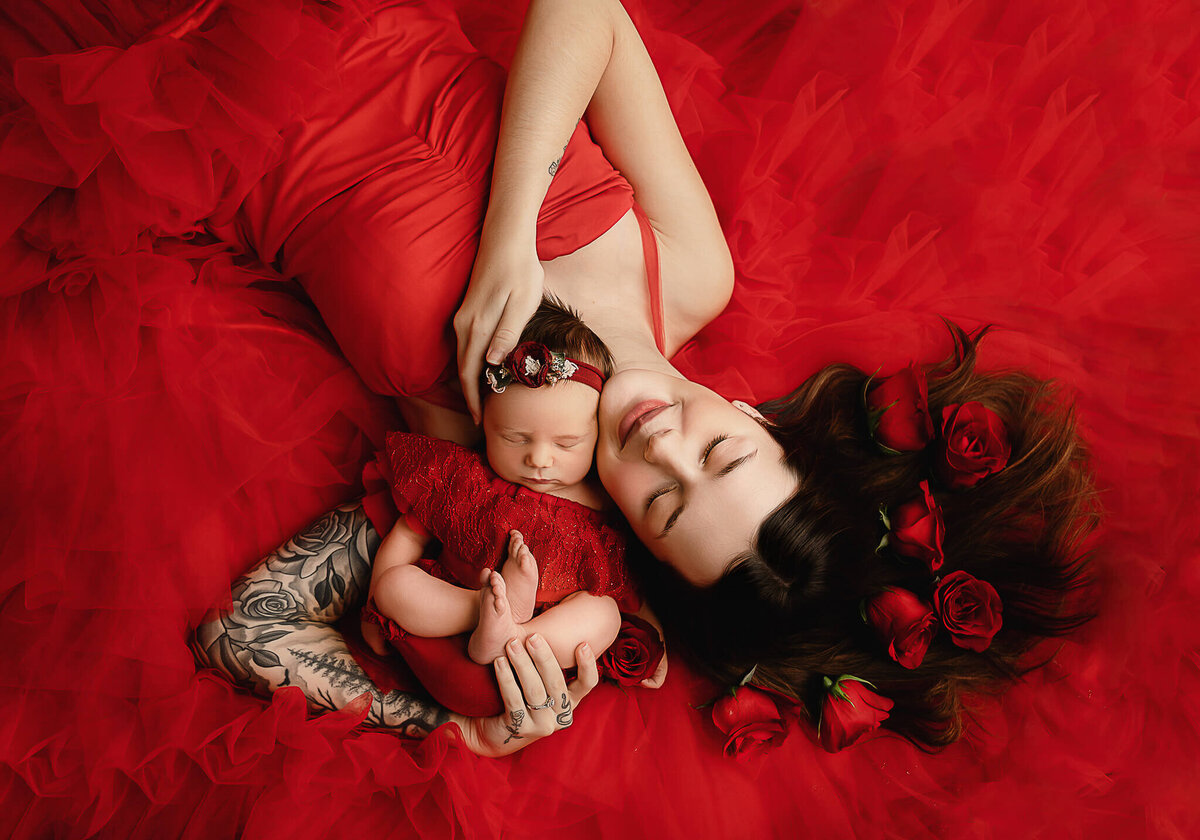 Stunning Greater Toronto Newborn portrait session  of mom and daughter photographed in red gown laying gown with red roses in mom's hair.