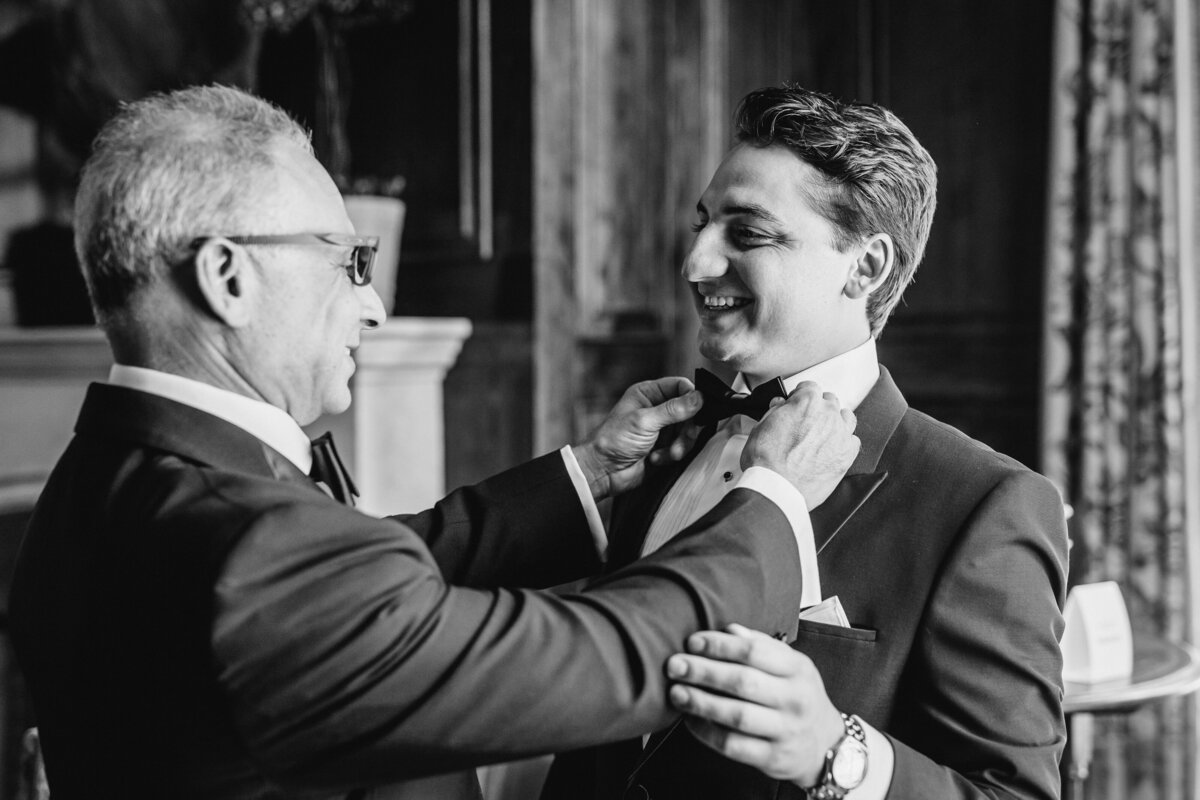 Black and white photo of groom and father adjusting bow tie before the ceremony at Old Edwards Inn wedding.
