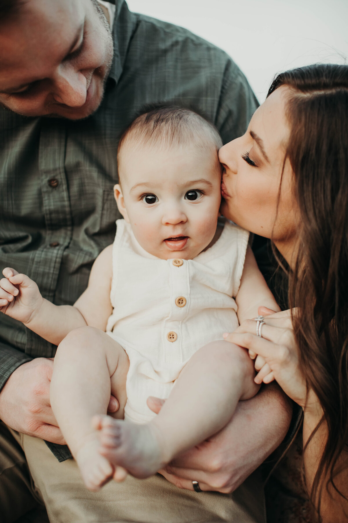 Close up of baby and mom kissing baby on forehead. 
