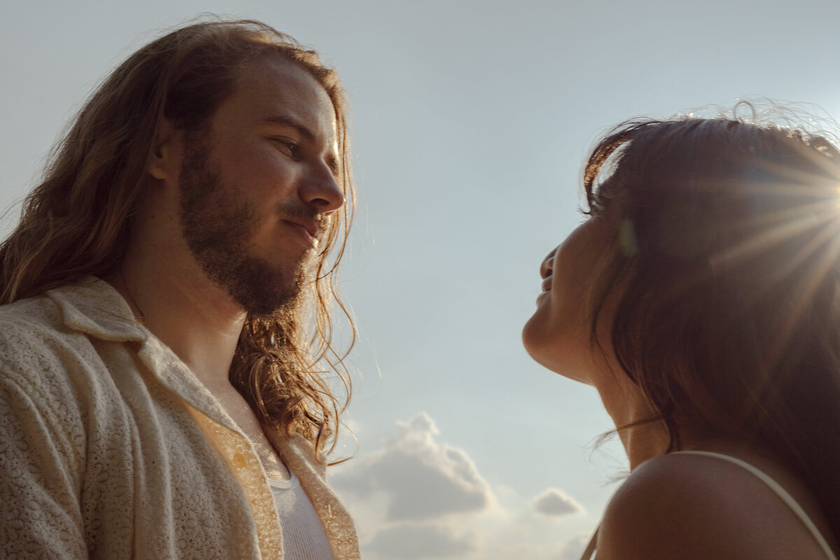 A romantic, sun-kissed close-up of a couple sharing an affectionate moment, illuminated by warm spring sunlight in the park near White Rock Lake, Dallas.