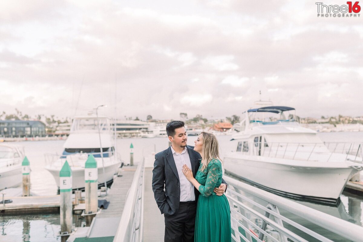 Tender moment for engaged couple while standing on the docks at Lido Marina Village