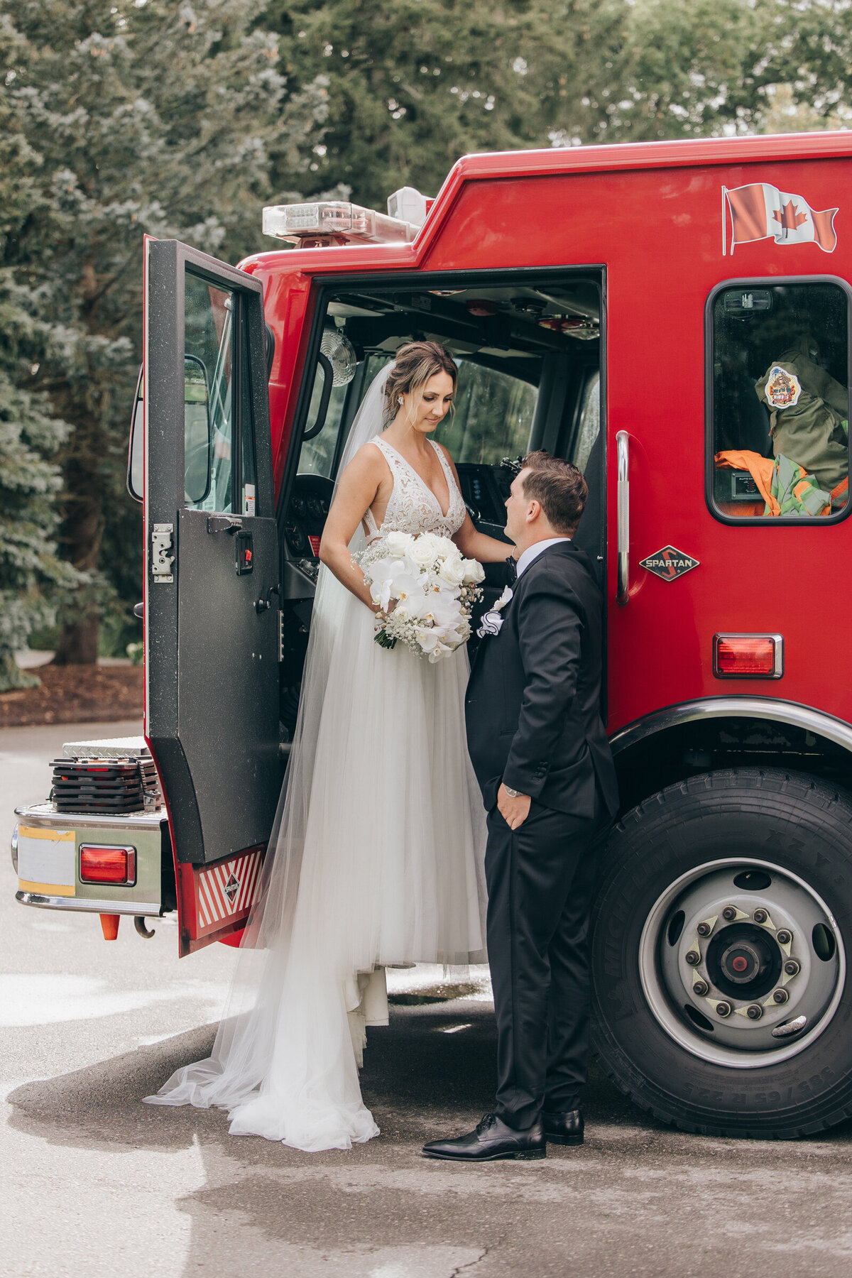 Bride and groom posing for portraits in front of a red fire truck