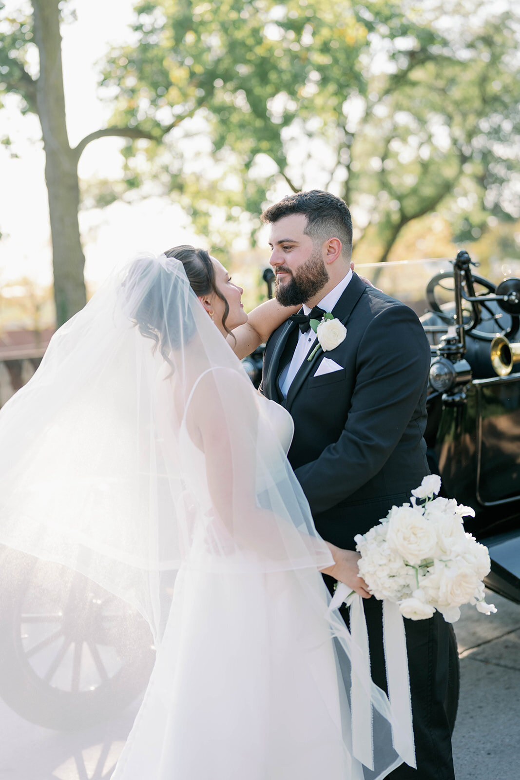 Romantic portrait of bride and groom near a vintage carriage at Dearborn Village Michigan, natural light wedding photos.