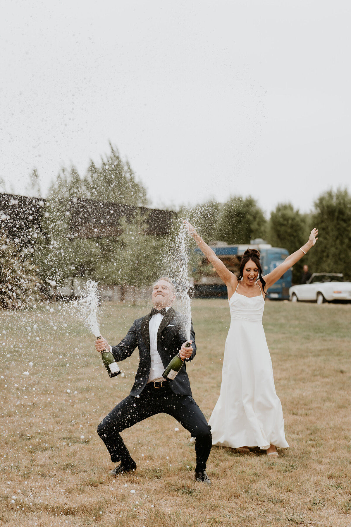 Bride and groom entering reception while spraying champagne 