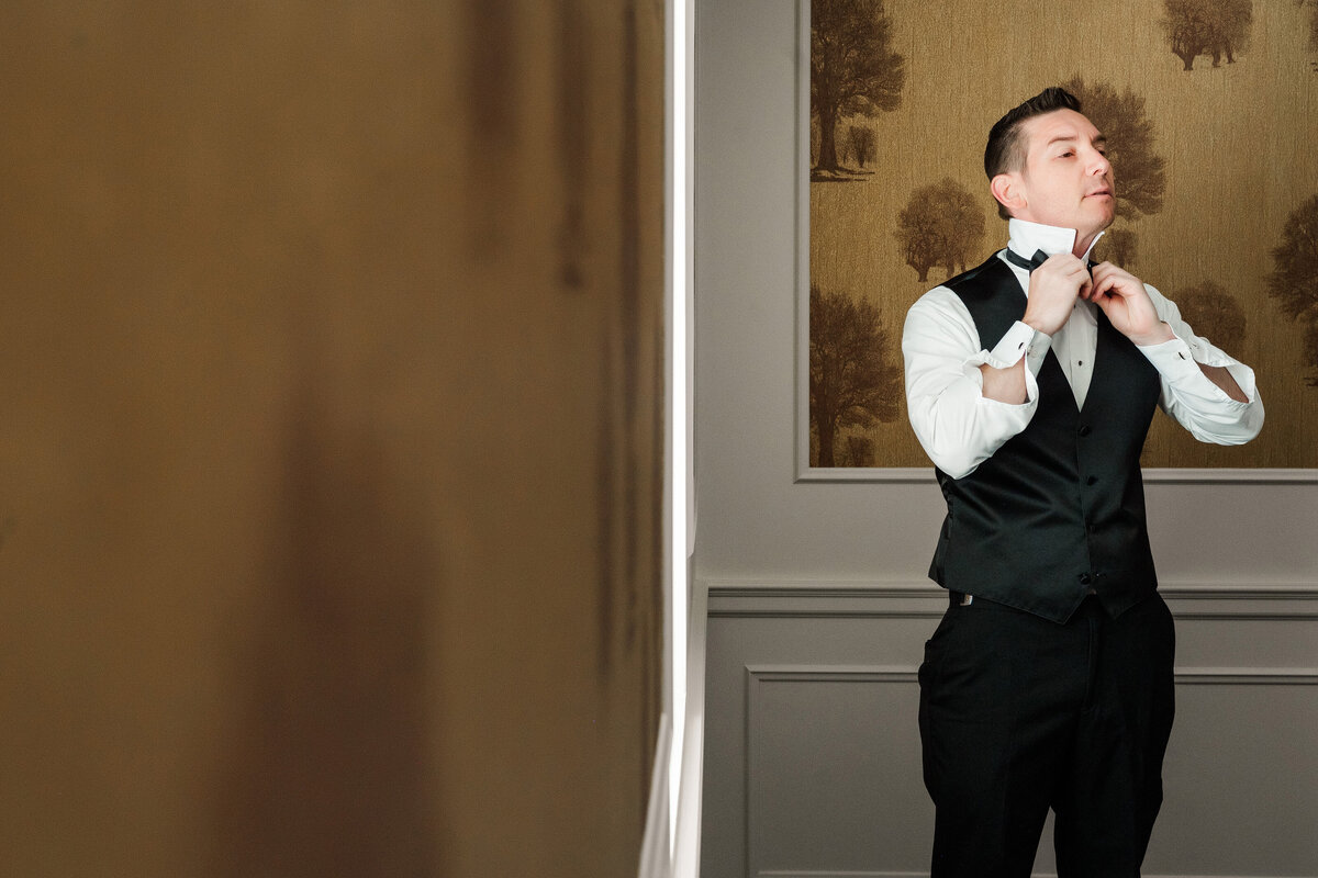 groom fixing his bowtie before his wedding cermeony