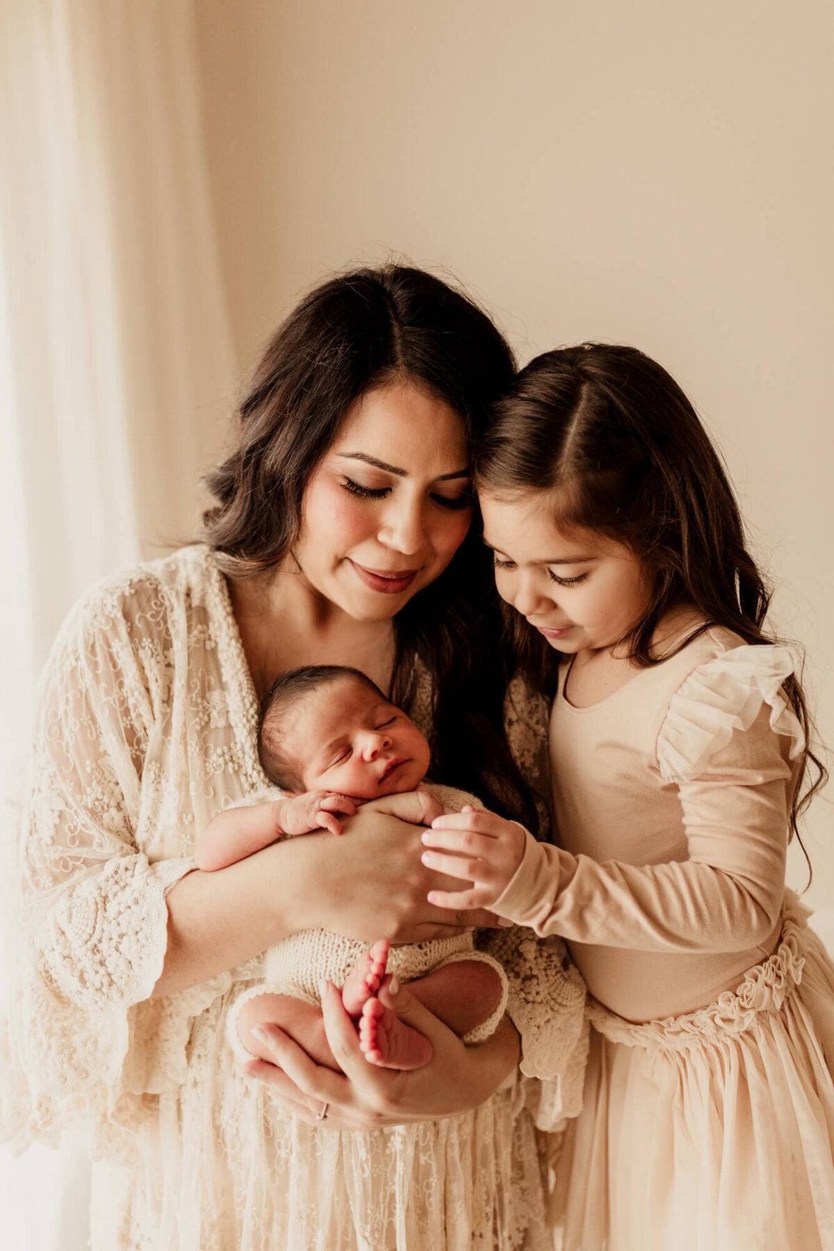 Mother wearing a lace dress with her daughter and her newborn baby boy, studio newborn session OKC.
