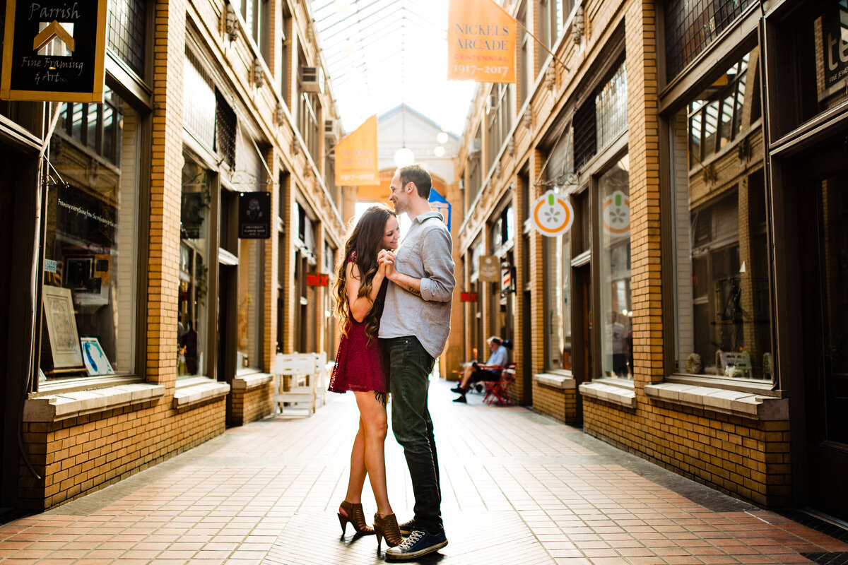 An engagement photo of a couple slow dancing in the middle of Nickels Arcade in Downtown Ann Arbor Michigan.  Photo By Adore Wedding Photography. Toledo Wedding Photographers