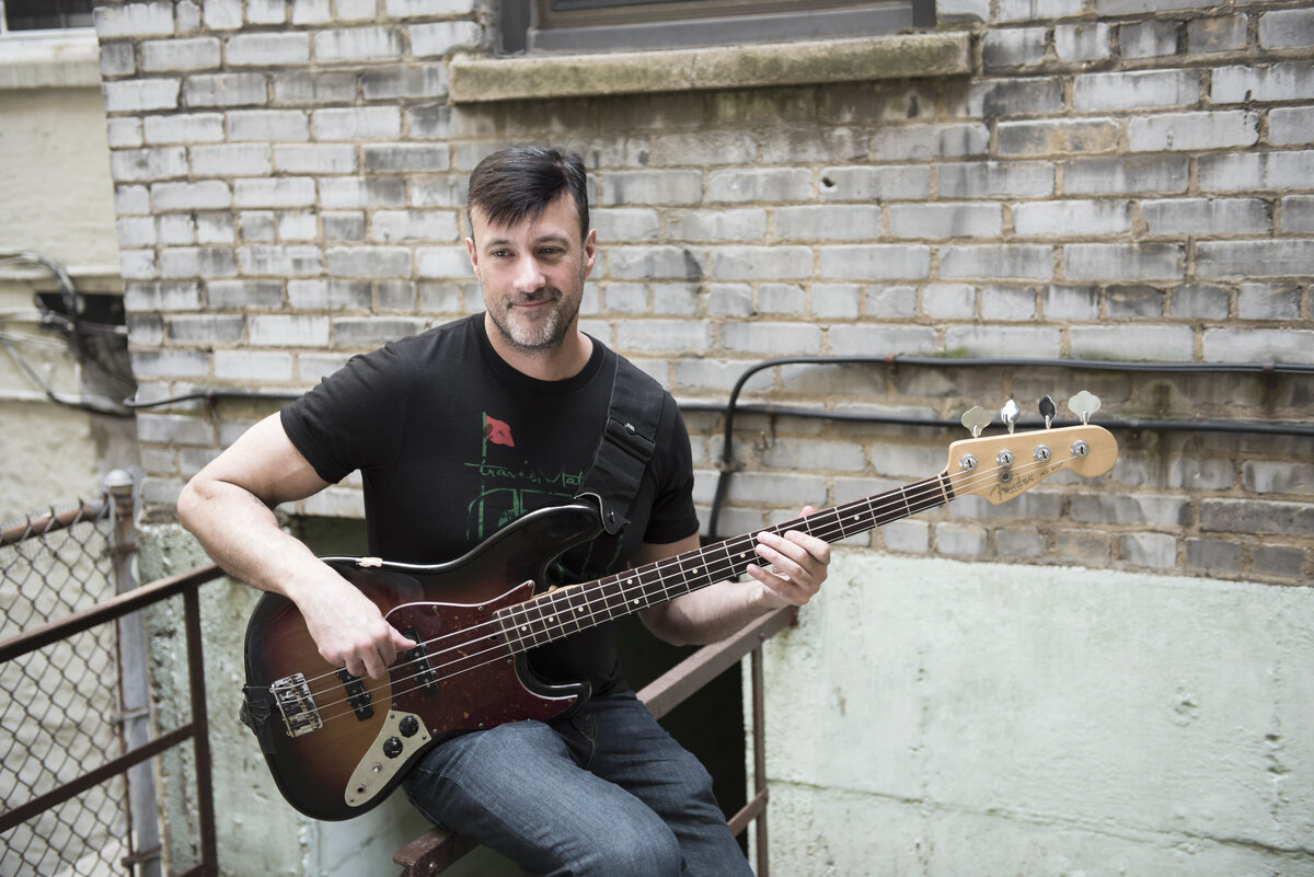 A person sitting outside playing bass