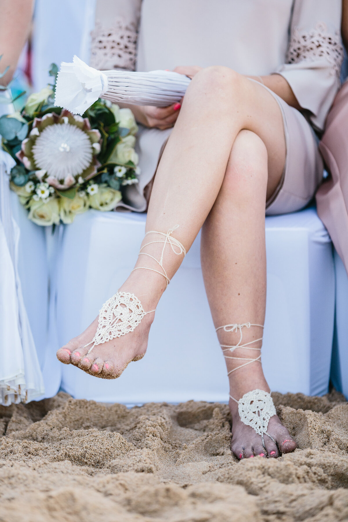 A person wearing handmade crocheted footwear on the beach. 