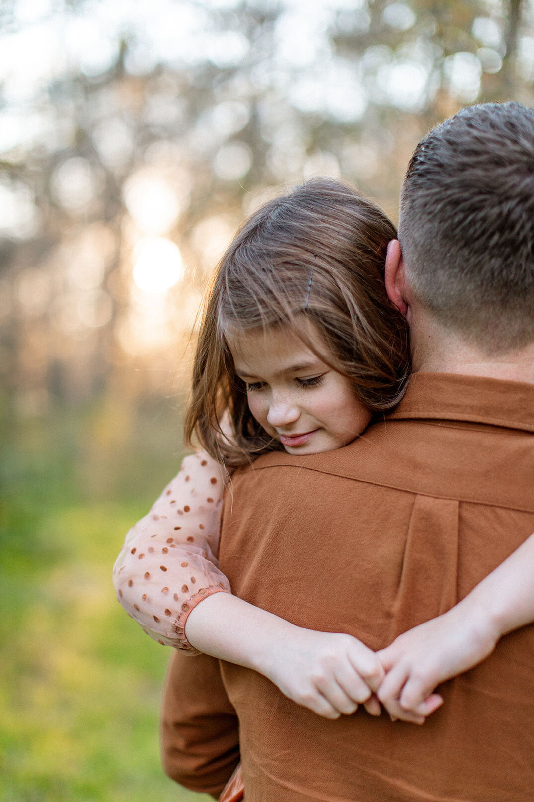 Outdoor family portrait of a daughter resting on her father's shoulders, captured by San Antonio photographer Sara James.