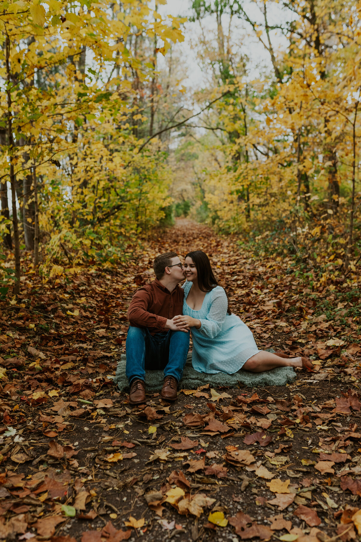 Engaged couple in an autumnal forest, capturing fall engagement in Indiana.