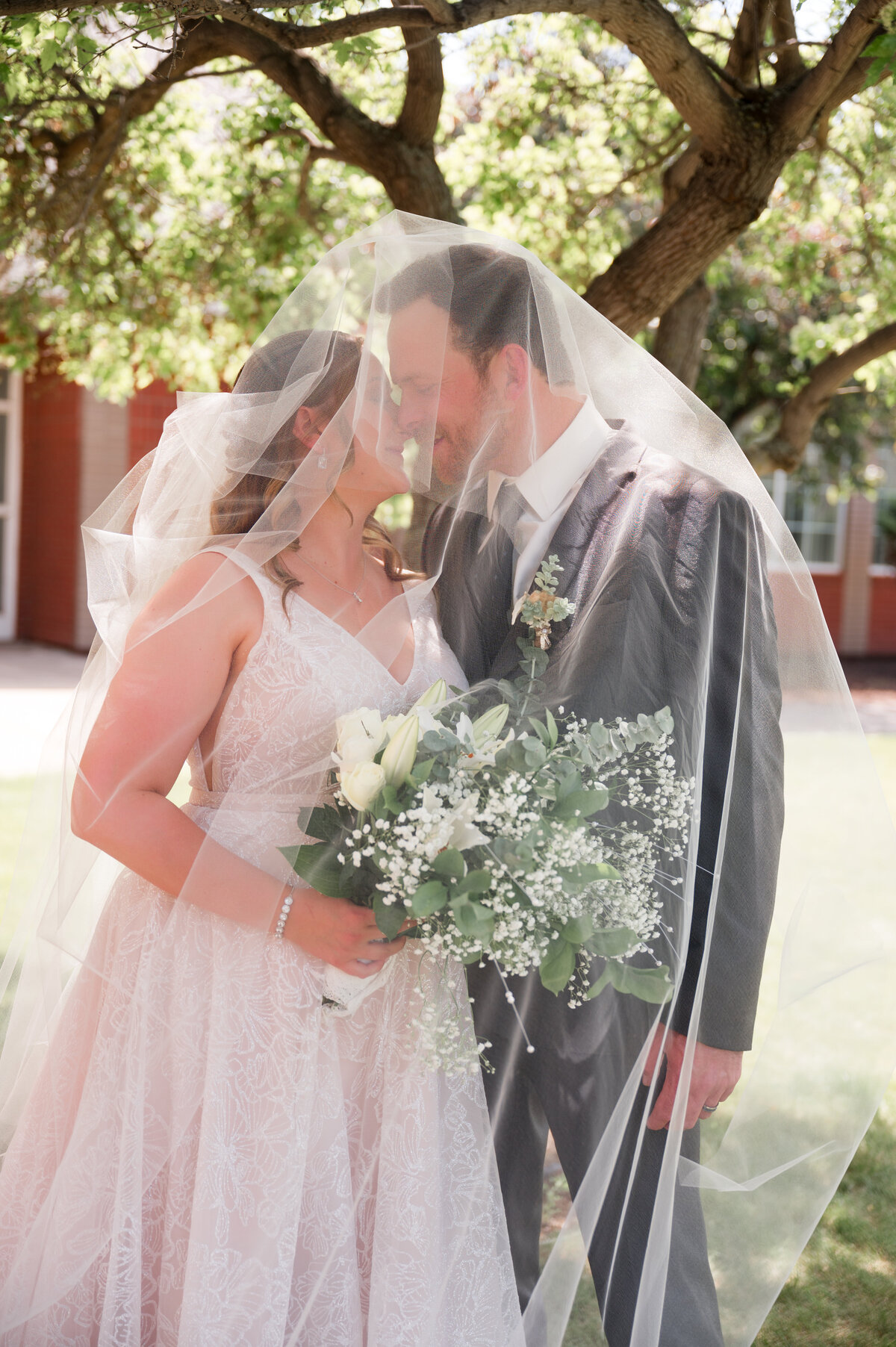 wedding couple under the veil kiss 