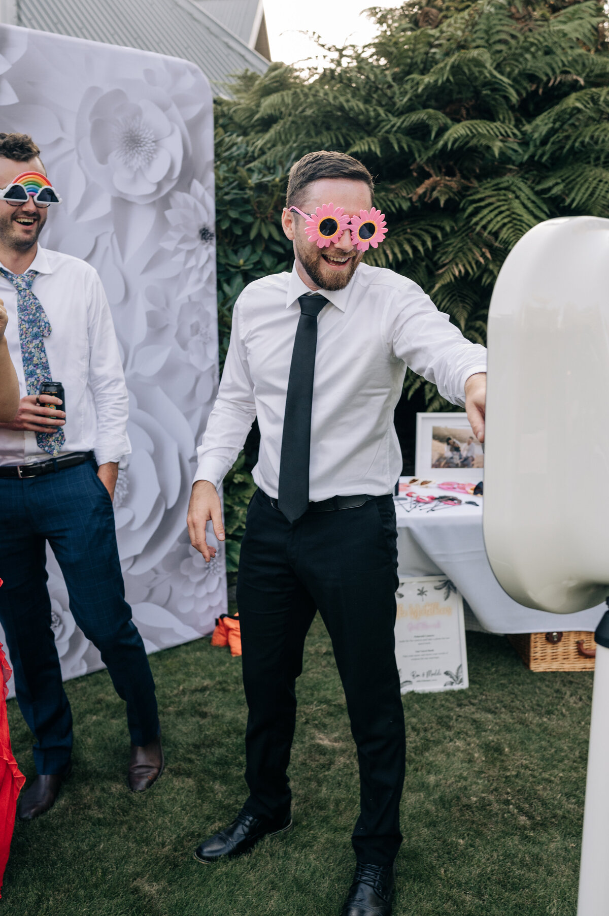 a wedding guest in white shirt and black tie uses the photo booth