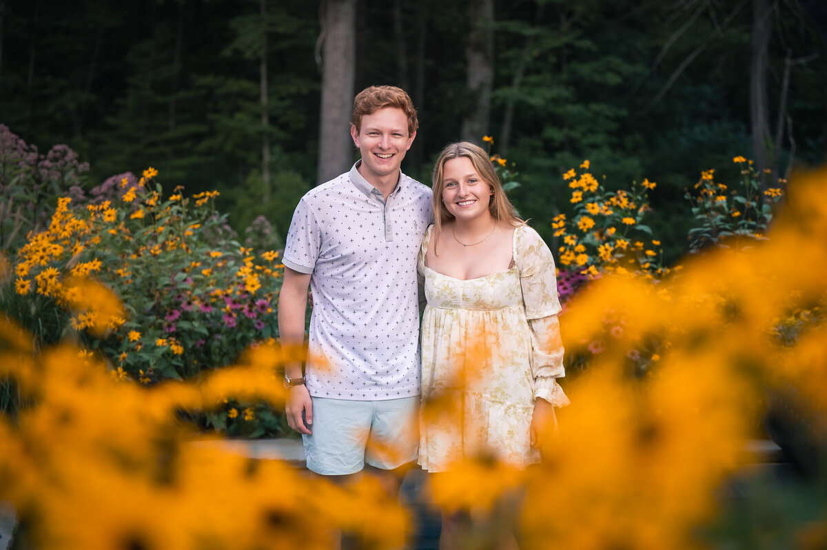 Brother and sister smiling for family portrait with native new england flowers in foreground and background