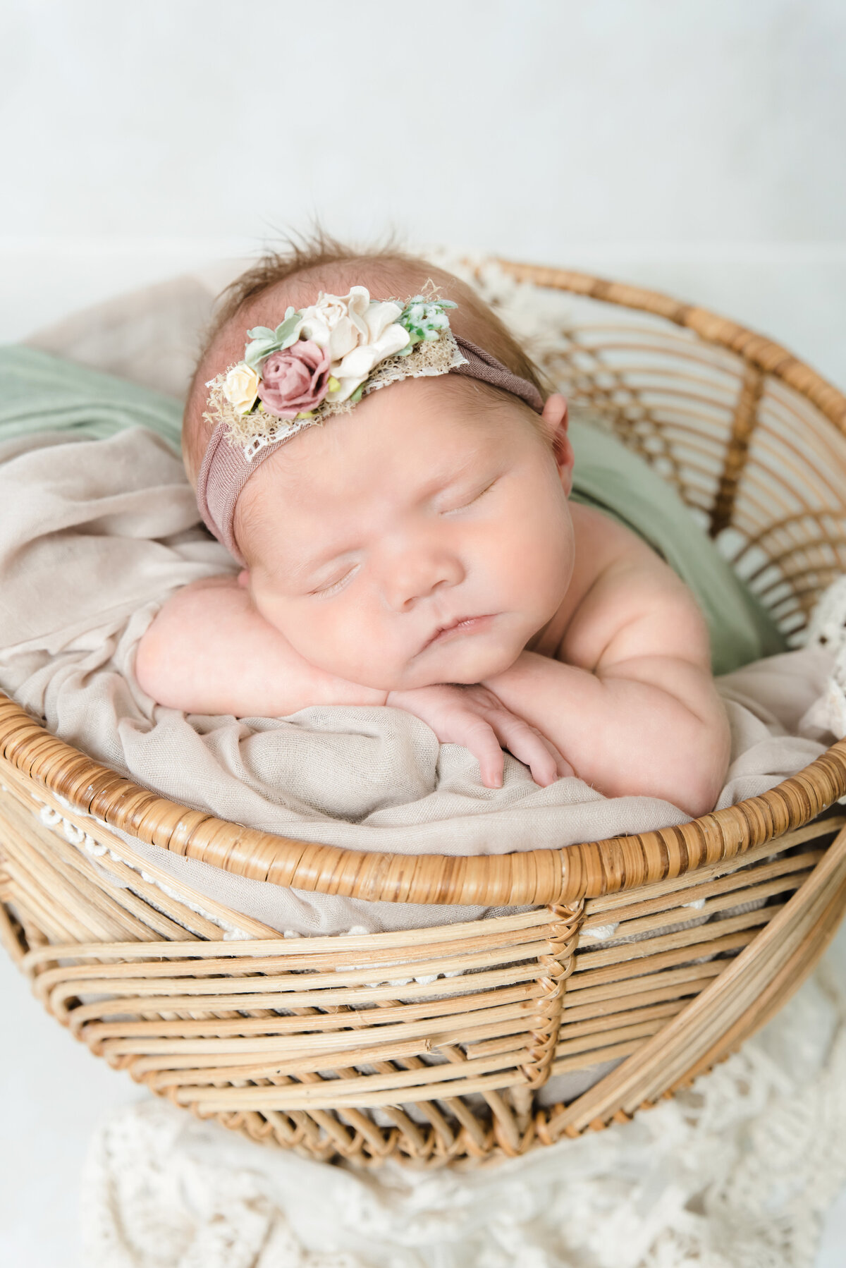 baby girl  wrapped in sage sleeps on belly in basket