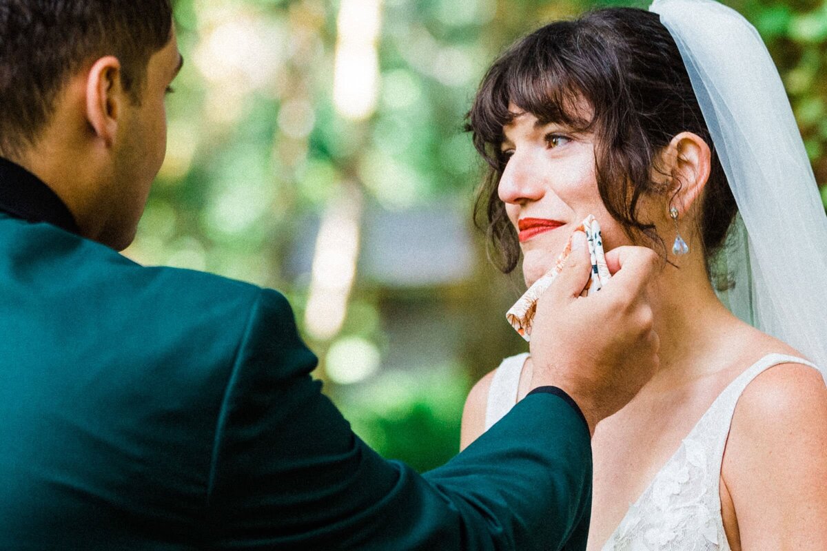 a groom wiping away his bride's tears after vow reading photographed by Alexandria, a Washington Elopement Photographer