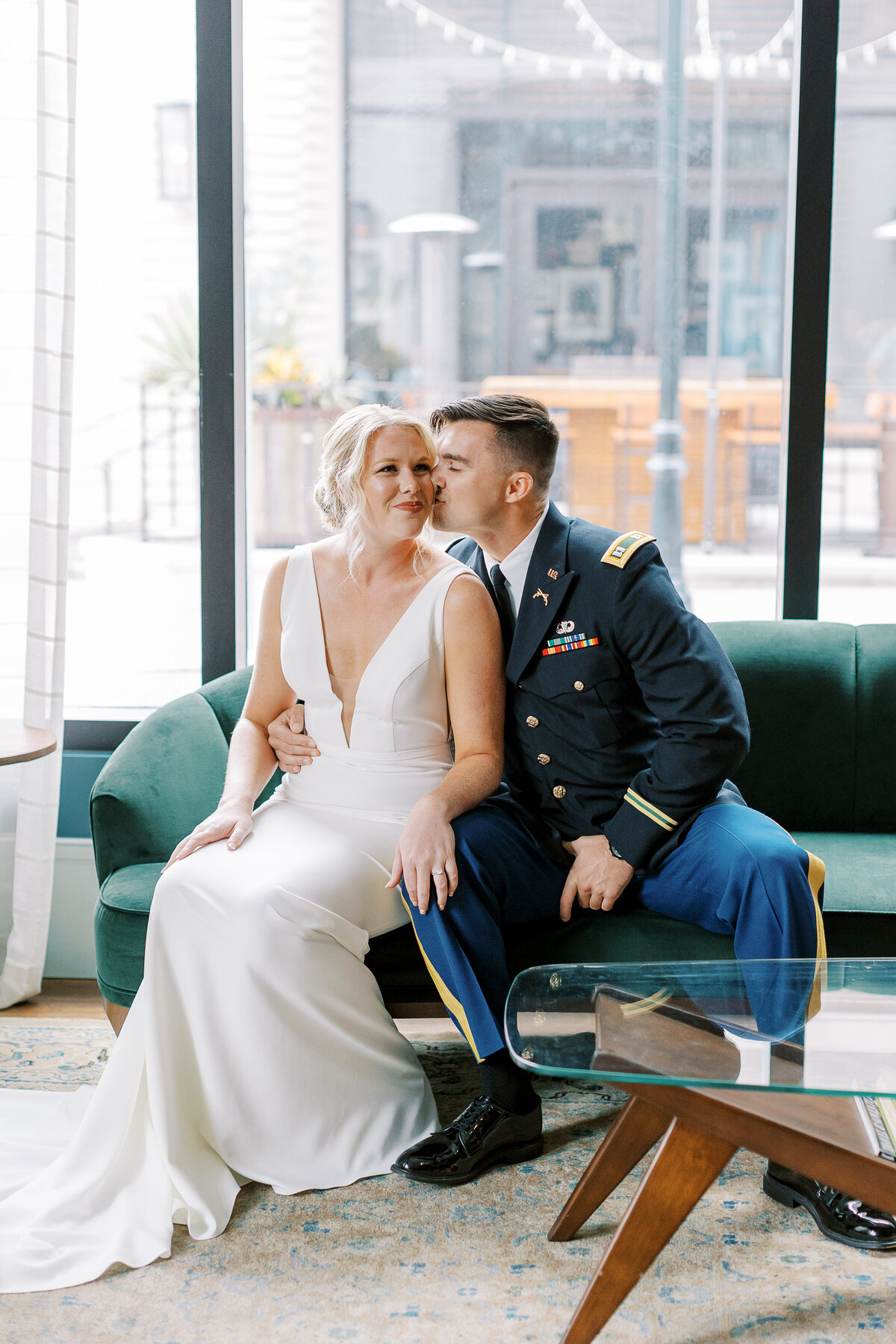 Military groom and bride kissing on a couch