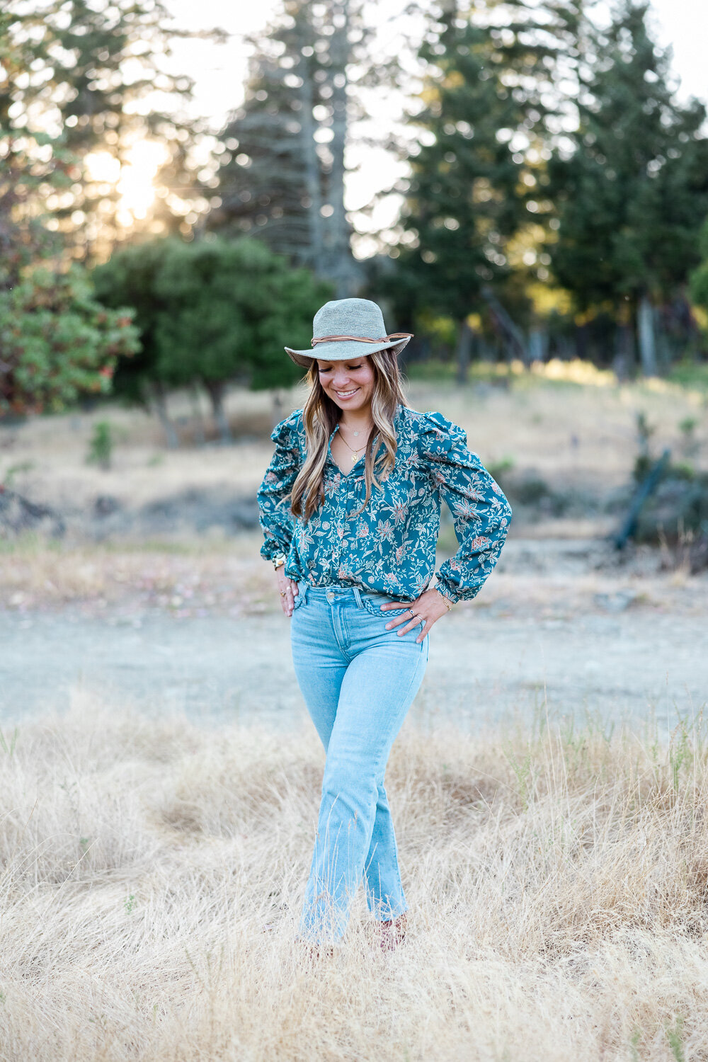 Woman walking in a Marin county field with her head looking down as she is walking.
