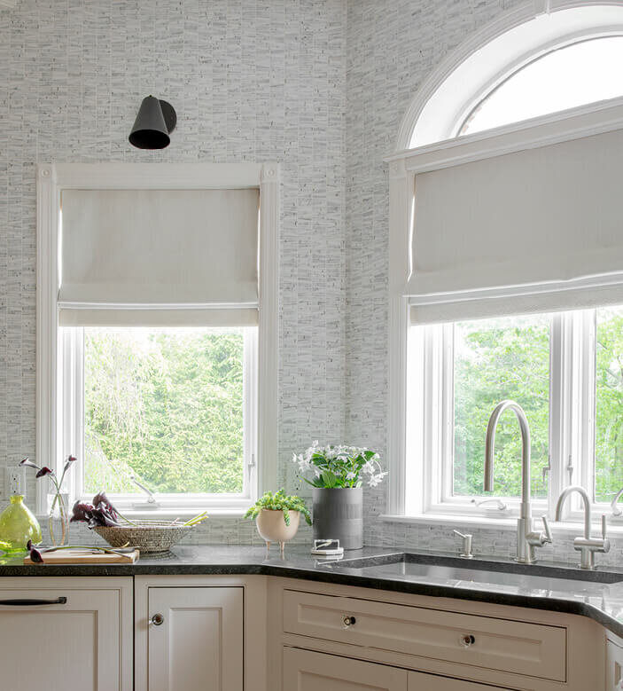 Kitchen and bath designers in Westwood create a light and white kitchen with dark grey counters, Ann Sacks backsplash tile, and Cedar and Moss wall sconces.