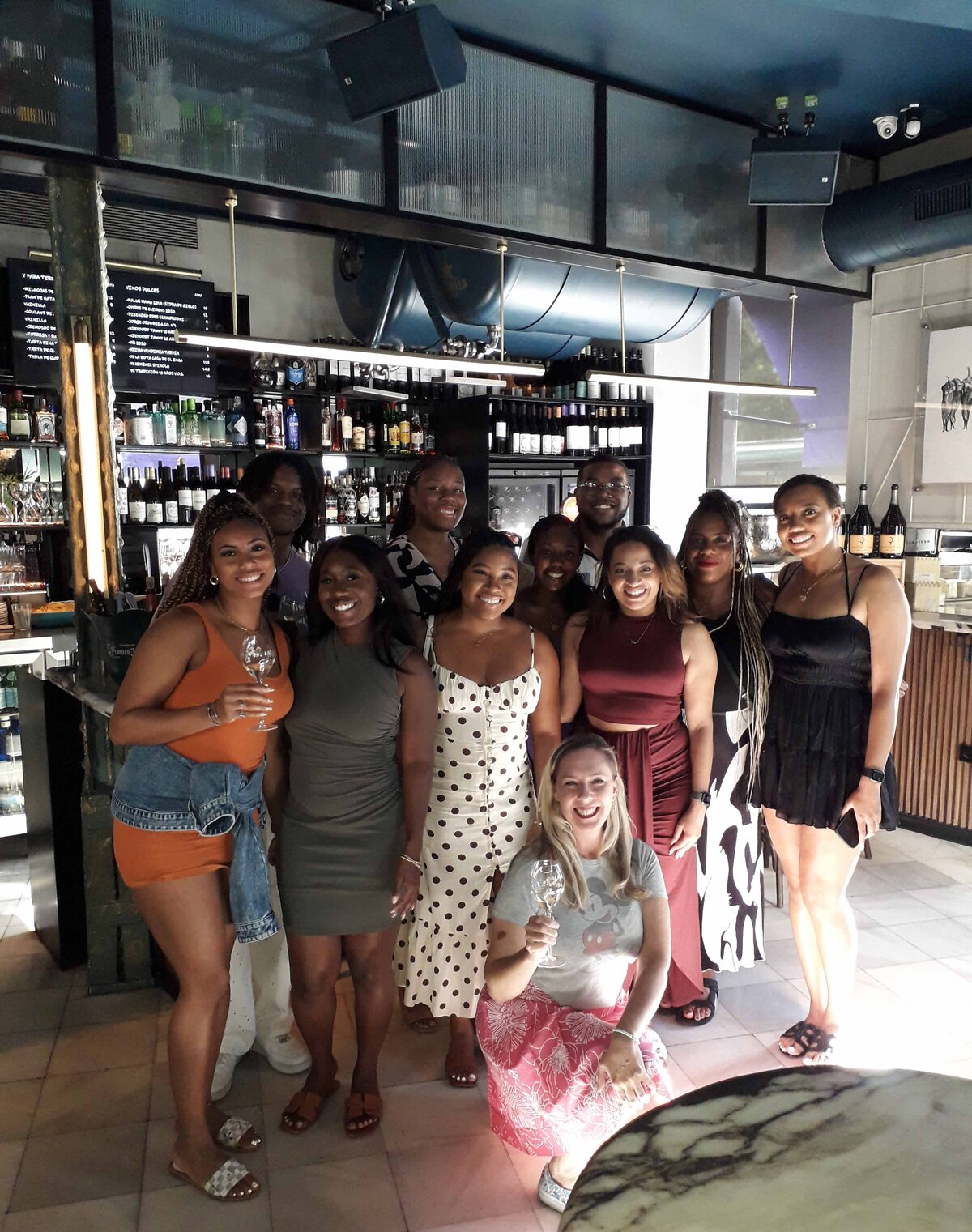 A group of women standing and posing for a photo with Wine Guide Maria Cristina Barrero at a tapas bar.
